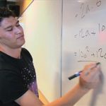 En ungdom skriver regnestykker på en tavle.
