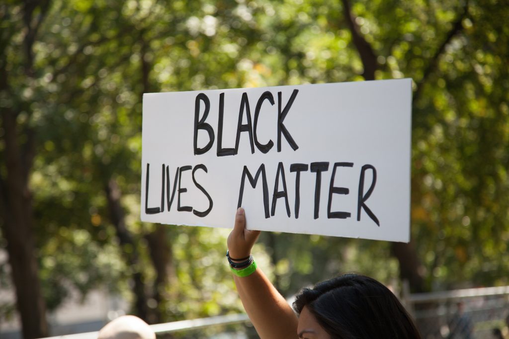 Kvinne holder opp skilt med teksten "Black Lives Matter"