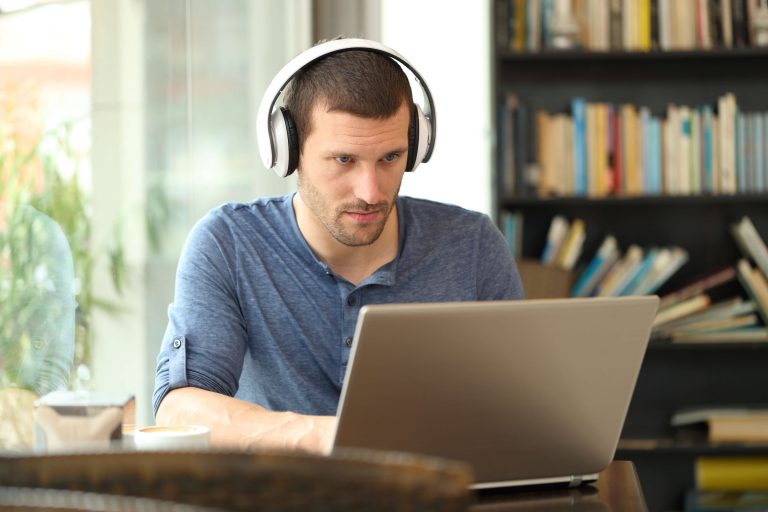 mann med headset sitter foran laptop og studerer