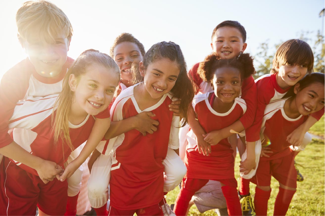 En gjeng barn i røde trøyer på fotballbanen.