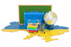 Foto av tavle, skolesekk, bøker, blyanter og en globus som er plassert på et ukrainsk kart i flaggfargene.