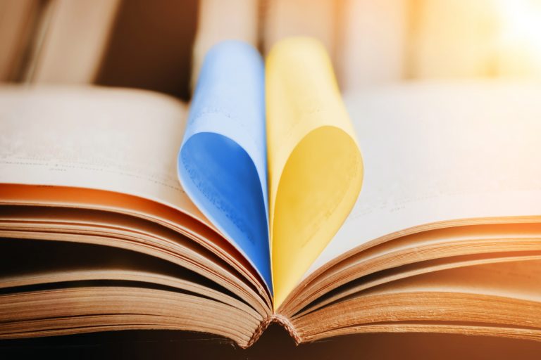 Foto av en oppslått bok der to av sidene er foldet som et hjerte med fargene fra det ukrainske flagget, blått og gult.