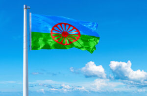 Foto av romfolkets flagg som vaier i vinden på en flaggstang