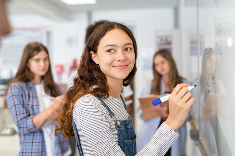 Foto av smilende elev som skriver på tavle