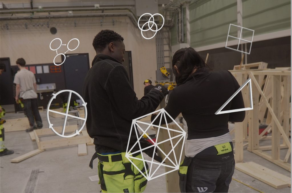 Foto av to elever som arbeider sammen i et verksted. På fotoet er det plassert ulike figurer som skal symbolisere ulike didaktiske modeller. Modellene er ikke gjenkjennbare. Vi kan anta at figuren fremst er den didaktiske ralsjonsmodellen.