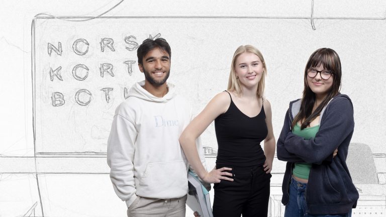 Foto av tre elever står foran en tavle hvor teksten norsk kort botid er skrevet.