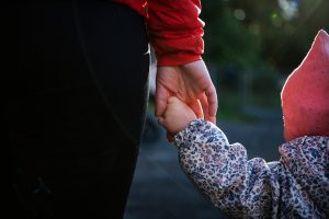 Foto av en voksen som holder et barn i hånden.