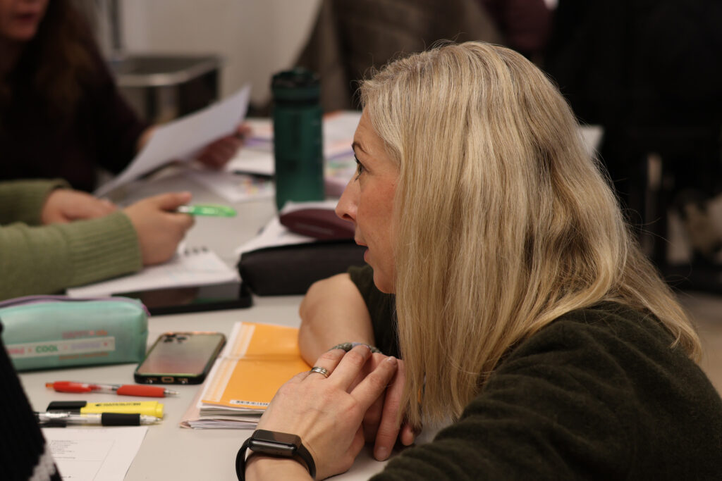 Foto av Hanne-Live i klasserommet som sitter ved et arbeidsbord.